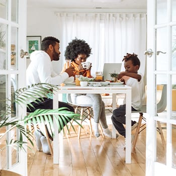 Family of three sitting at dining room table eating a meal together