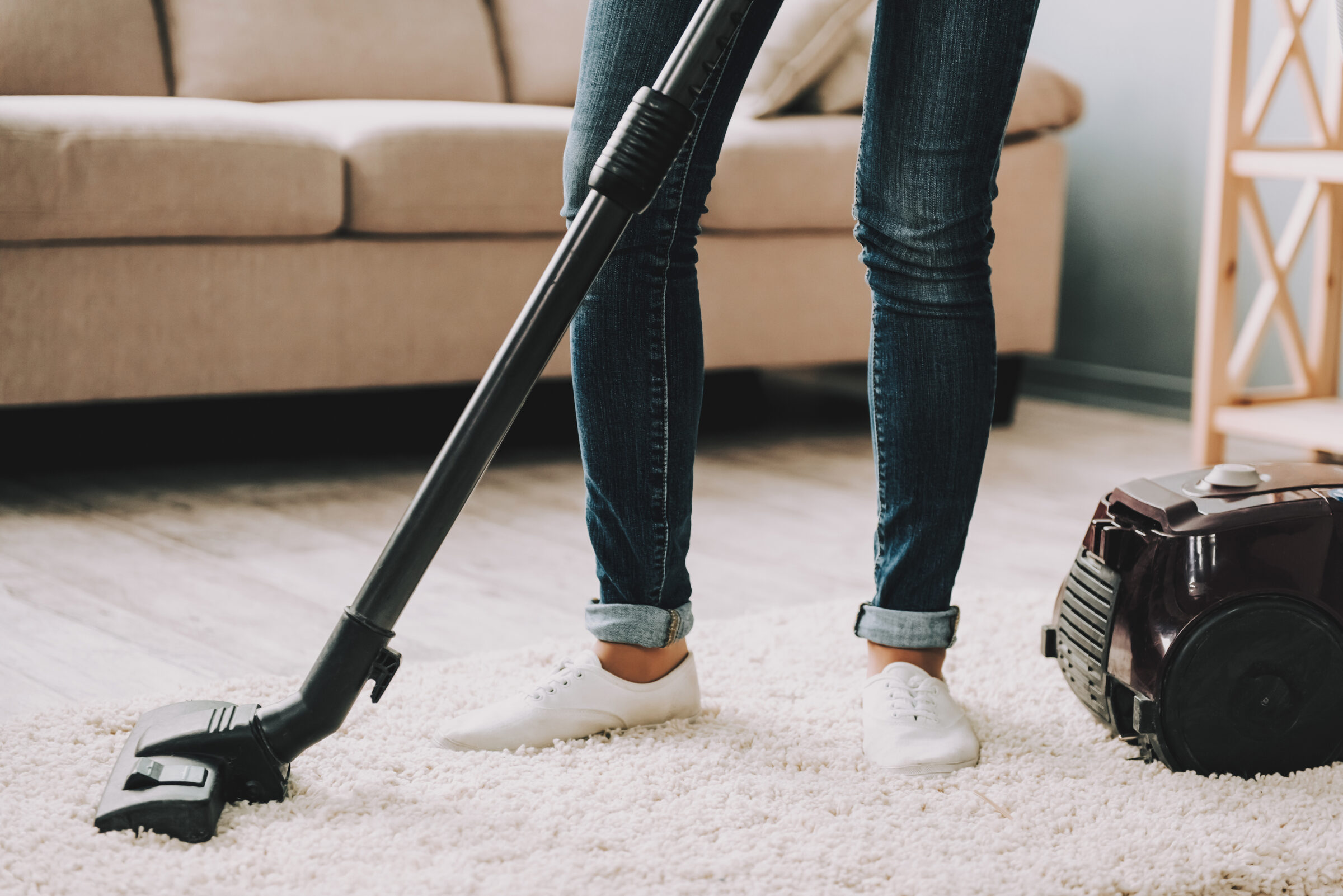 Lady's legs in jeans sweeping floor rug