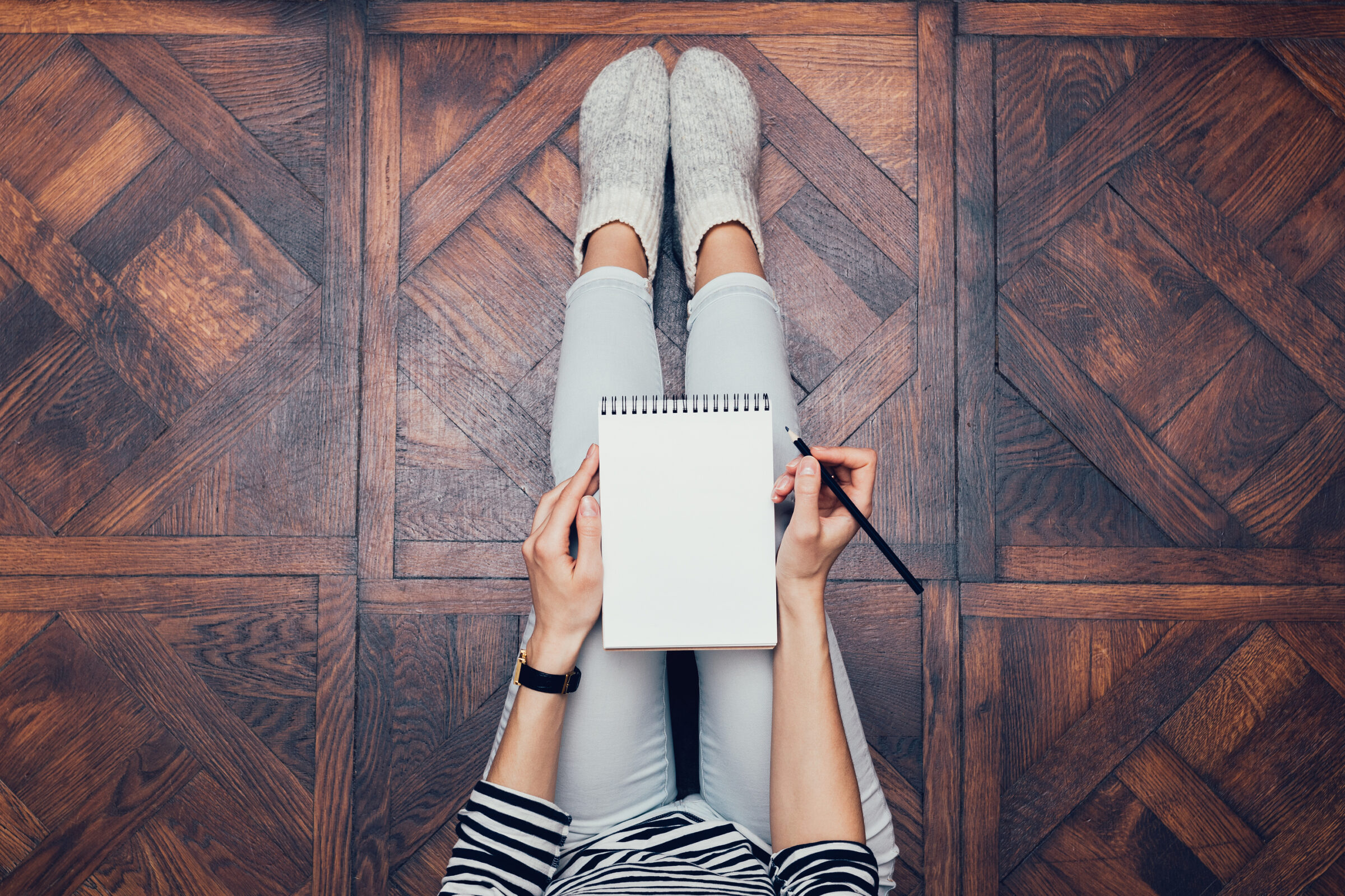 girl sitting on wood floor with notebook