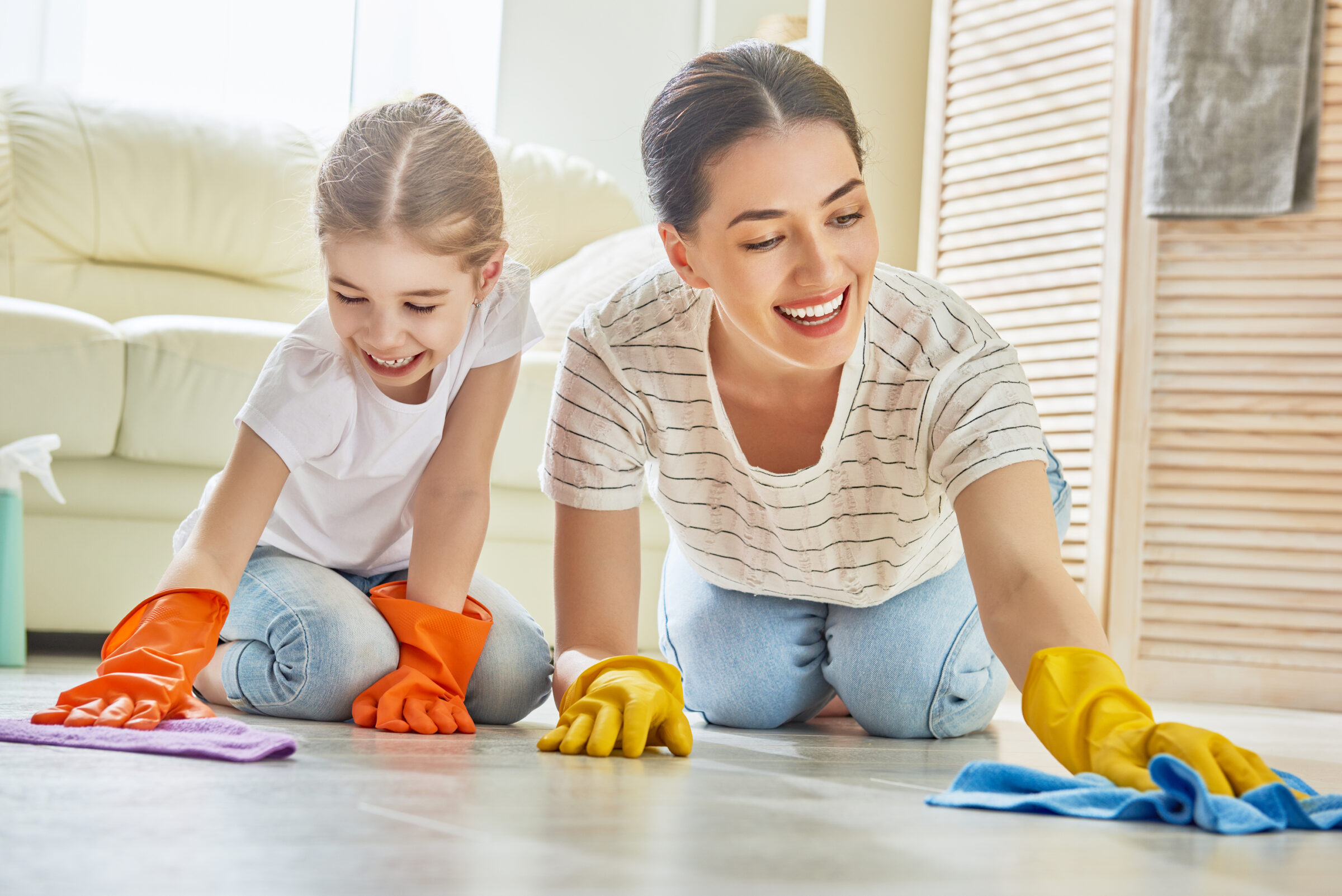 mother and daughter cleaning floor together with smiles